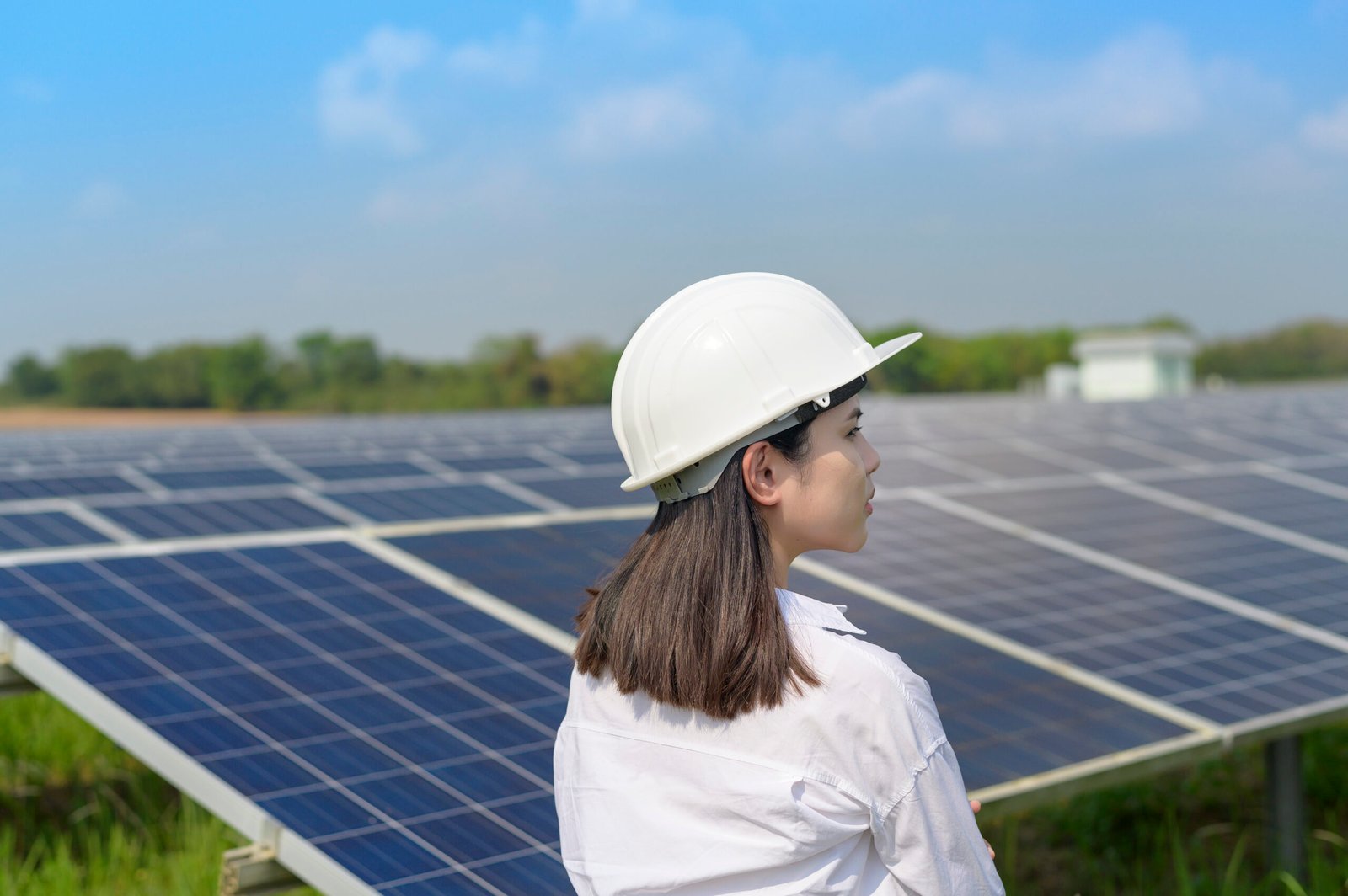 Afemale engineer wearing helmet in Photovoltaic Cell Farm or Solar Panels Field, eco friendly and clean energy.